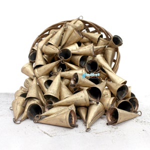 May include: A large pile of gold-coloured metal bells, spilling out of a wicker basket. The bells are cone-shaped with a small loop at the top.