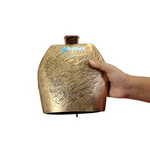 The bell held in hand showing its jumbo size in comparison to the the hand size.