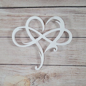 May include: White wooden cutout of an infinity symbol intertwined with a heart shape. The cutout is on a light brown wood background.
