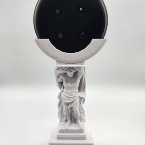 Peut inclure: Une statue blanche en 3D d'une figure classique tenant un haut-parleur intelligent noir. Le haut-parleur a quatre boutons sur le dessus.