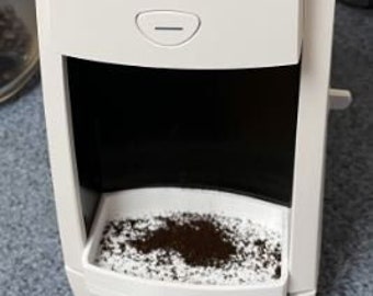 Puede incluir: Un molinillo de café Baratza Encore blanco con una tolva negra y un recipiente transparente lleno de café molido. El molinillo tiene un dial con los números del 1 al 30.