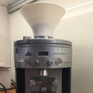 Puede incluir: Un molinillo de café plateado y negro con una tolva blanca y una pantalla digital que dice "Grind on Demand".