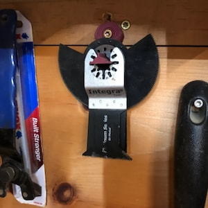 Puede incluir: Una cuchilla multiherramienta oscilante negra y plateada con un inserto de plástico rojo. La cuchilla está etiquetada como "Integra Tools" y "Premium Series" con el texto "Bi-Metal" en el lateral.