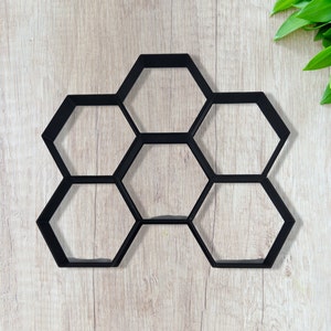 May include: Black plastic mold for making concrete stepping stones. The mold is shaped like a honeycomb with six hexagonal sections.