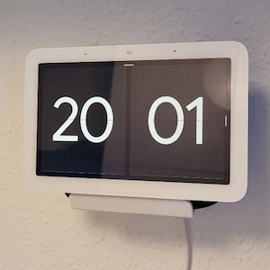 Peut inclure: Un écran intelligent Google Nest Hub Max blanc avec un écran noir affichant l'heure "20 01".
