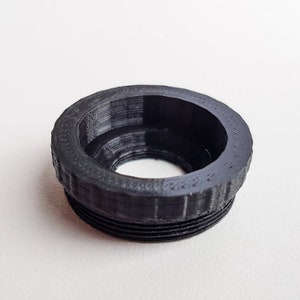 May include: Black plastic camera lens adapter ring with a threaded outer edge.