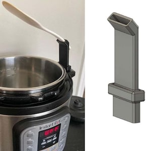 May include: A black Instant Pot electric pressure cooker with a white spatula resting on a black holder attached to the side of the pot. The pot has a digital display with the text "Instant Pot" and a variety of buttons, including "Soup/Broth", "Meat/Stew", "Bean/Chili", "Rice", "Porridge", "Slow Cook", "Pressure Cook", "Yogurt", "Sauté", "Keep Warm", "Manual", "More", "Less", "Cancel", and "Timer".