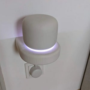 May include: A white wall-mounted router with a purple light ring around the base. The router is plugged into a white electrical outlet.