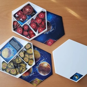 Puede incluir: Organizadores de juegos hexagonales blancos con compartimentos que contienen piezas de juego. Las piezas son rojas, amarillas y azules. Las piezas del juego están sobre una superficie de madera. También hay tableros de juego hexagonales azules y blancos.