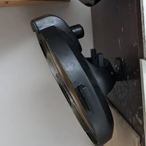 May include: A black, round, ceiling light fixture with a silver trim. The light is mounted to a wall with a black bracket.