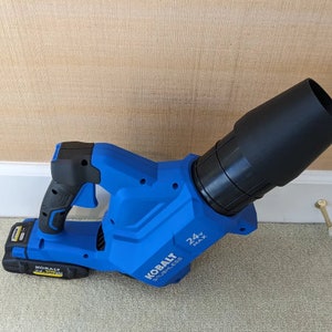 May include: A blue and black cordless leaf blower with a 24V MAX battery. The blower has a long nozzle and a comfortable handle.