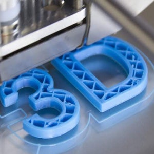 May include: A 3D printer creating a blue plastic model of the letters "3D".