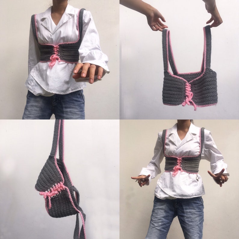 K&ouml;nnte beinhalten: Ein graues H&auml;keltop mit rosa Besatz und einer Schn&uuml;rung vorne. Das Top wird an einem Modell gezeigt und an einem Haken aufgeh&auml;ngt.