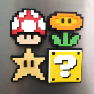 May include: Four pixel art magnets featuring characters from the Super Mario Bros. video game series. The magnets are red and white mushroom, a yellow flower with green leaves, a yellow star with a black outline, and a yellow question block with a black outline and a white question mark.