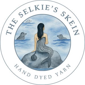 May include: Circular logo with the text "The Selkie's Skein Hand Dyed Yarn." The image features a mermaid sitting on a rock with seals in the water. The mermaid has a knitted tail and is holding a ball of yarn.