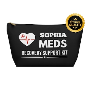 Op de afbeelding: Zwarte etui met ritssluiting met de tekst "SOPHIA MEDS RECOVERY SUPPORT KIT" in het wit. Een witte hart met een rode kruis- en hartslagafbeelding staat links. Een gouden "Premium Quality" zegel staat rechtsboven.