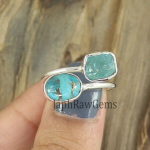 Puede incluir: Dos anillos de plata con piedras preciosas turquesa y aguamarina. Los anillos est&aacute;n apilados uno sobre el otro y se llevan en un dedo. El texto "JaphRawGems" es visible en la parte inferior de la imagen.