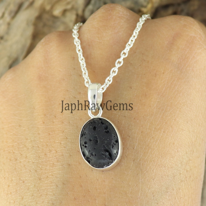 May include: A silver chain necklace with a black oval pendant featuring a lava rock. The pendant is set in a silver bezel.