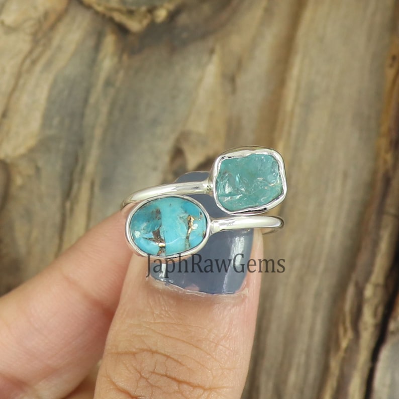 Puede incluir: Un anillo de plata con dos piedras turquesa. El anillo est&aacute; engastado con una piedra turquesa ovalada m&aacute;s grande y una piedra turquesa cuadrada m&aacute;s peque&ntilde;a. El anillo est&aacute; en un dedo.