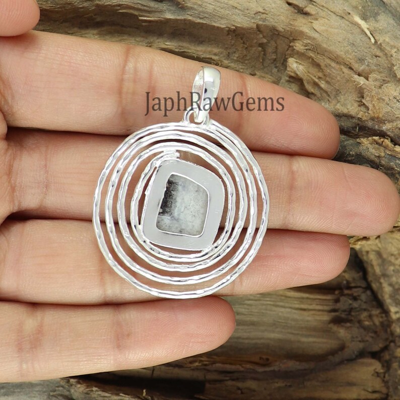 K&ouml;nnte beinhalten: Ein silberner Anh&auml;nger mit einem einzigartigen Design. Der Anh&auml;nger hat einen quadratischen Mittelstein mit schwarz-wei&szlig;en Mustern, umgeben von konzentrischen Kreisen. Der Text "JaphRawGems" ist auf dem Bild sichtbar.