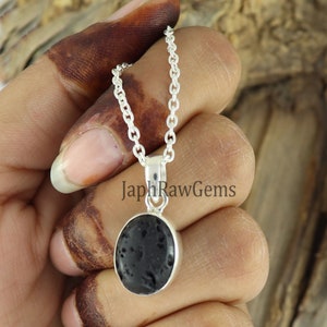 May include: A silver chain necklace with a black oval pendant made of lava rock. The pendant is set in a silver bezel.