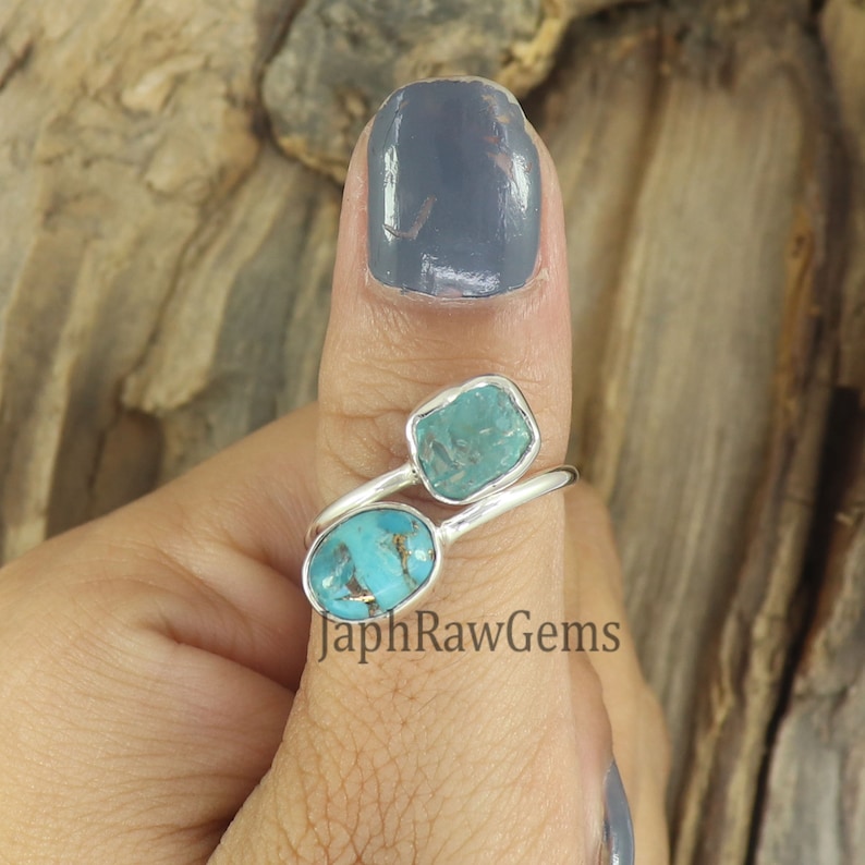 Puede incluir: Un anillo de plata con dos piedras turquesa. El anillo est&aacute; en el pulgar de una persona. Las piedras son de diferentes formas y tama&ntilde;os. El anillo es de JaphRawGems.