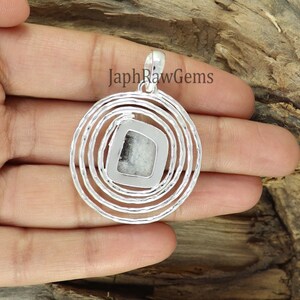 K&ouml;nnte beinhalten: Silberanh&auml;nger mit einem quadratischen, wei&szlig;-schwarzen Stein in der Mitte, umgeben von konzentrischen Kreisen. Der Anh&auml;nger hat eine Schlaufe f&uuml;r eine Kette. Der Text "JaphRawGems" ist im Bild sichtbar.
