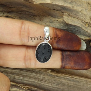 May include: A silver pendant featuring a black oval-shaped lava rock. The pendant is set in a silver bezel and has a silver bail for attaching to a chain.