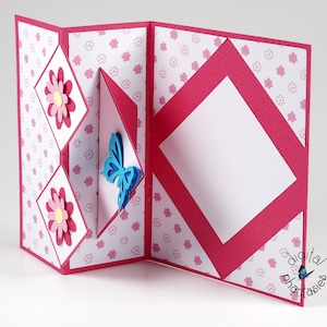 May include: A pink and white patterned card with a pop-up butterfly and flowers. The card is folded in half and has a blank space for a message.