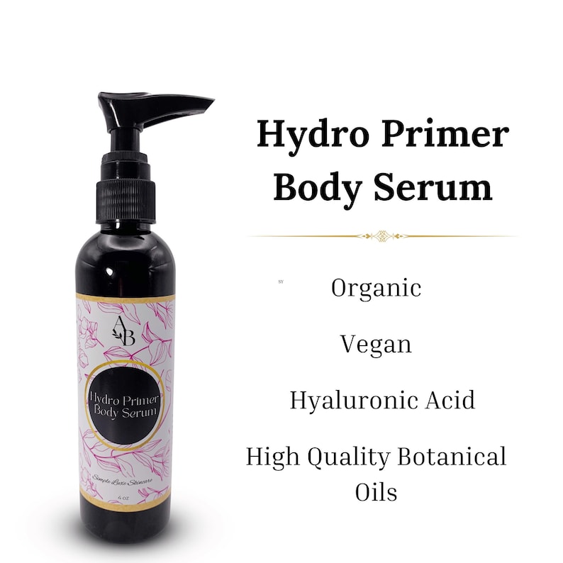 May include: A black pump bottle of Hydro Primer Body Serum with a white label and pink floral design. The label says "Hydro Primer Body Serum" and "Organic, Vegan, Hyaluronic Acid, High Quality Botanical Oils".