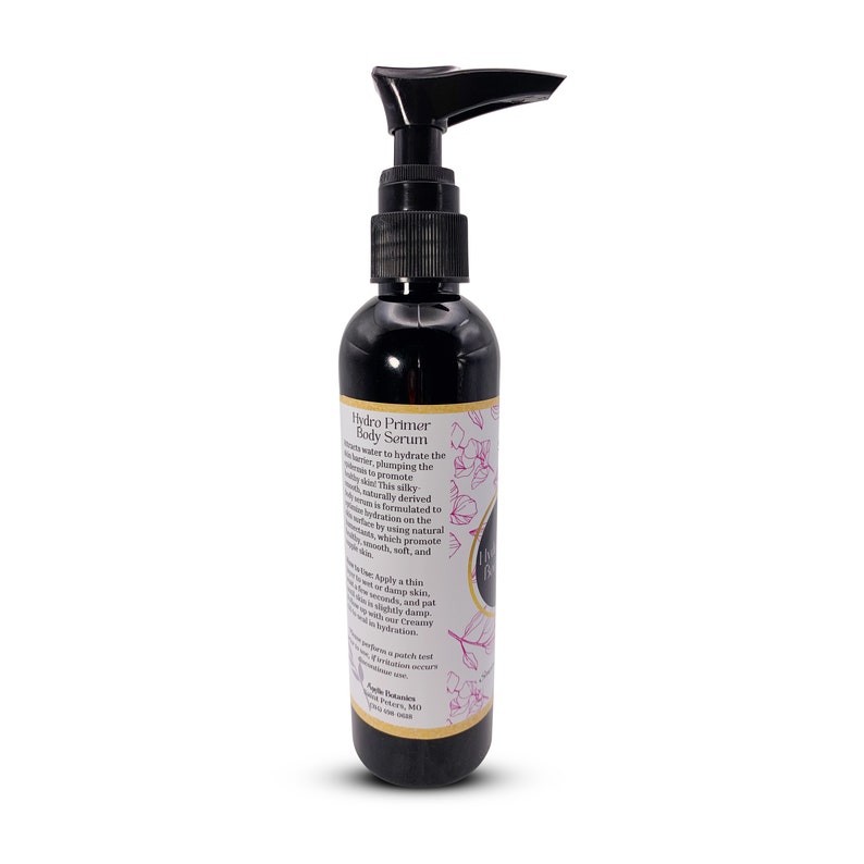 May include: A black bottle with a pump dispenser containing Hydro Primer Body Serum. The bottle has a gold label with pink floral accents and the text "Hydro Primer Body Serum".