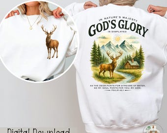 May include: White sweatshirt featuring a watercolor illustration of a deer on the front and back. The back design includes text that reads "IN NATURE'S MAJESTY GOD'S GLORY IS DISPLAYED" with a scenic landscape and Bible verse.