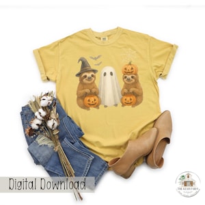 May include: Mustard yellow t-shirt featuring a Halloween-themed graphic. The graphic includes two sloths holding jack-o'-lanterns, a ghost, bats, and a spiderweb. The words "Digital Download" are printed at the bottom of the image.