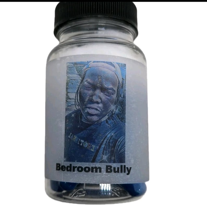Puede incluir: Una botella de vidrio transparente con tapa negra, que contiene c&aacute;psulas azules. La botella tiene una etiqueta con una imagen azul y blanca de una persona y las palabras "Bedroom Bully".