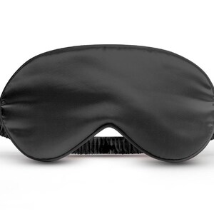 May include: A black sleep mask made of soft, silky material. The mask is designed to block out light and help you sleep.