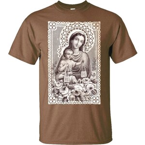 Puede incluir: Una camiseta marr&oacute;n con una imagen vintage de Mar&iacute;a y Jes&uacute;s impresa en la parte delantera. La imagen est&aacute; rodeada de un marco de encaje blanco y presenta detalles florales.