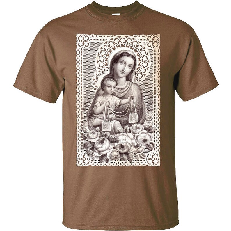 Puede incluir: Una camiseta marr&oacute;n con una imagen vintage de Mar&iacute;a y Jes&uacute;s impresa en la parte delantera. La imagen est&aacute; rodeada de un marco de encaje blanco y presenta detalles florales.