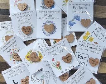 May include: A collection of memorial keepsakes, each featuring a small wooden heart engraved with the words Thank You, attached to a white card printed with In loving memory of, a name, dates, and various floral or symbolic illustrations.