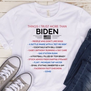 Puede incluir: Una camiseta blanca con un estampado gráfico que dice "Things I trust more than Biden" con una lista de cosas en las que la persona confía más que en Biden. La lista incluye: personas a las que no les gustan los perros, una serpiente de cascabel con un cartel de "acaríciame", cócteles con Bill Cosby, Casey Anthony dirigiendo una guardería, sushi de gasolinera, un balón de fútbol relleno por Tom Brady, consejos de inversión de Martha Stewart, agua del grifo de Flint, Michigan, un correo electrónico que dice que heredé una SIM, verificadores de hechos de Facebook y COVID.