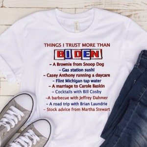 Puede incluir: Camiseta blanca con un gráfico rojo, blanco y azul que dice "THINGS I TRUST MORE THAN BIDEN" y enumera una serie de elementos humorísticos.