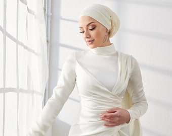 May include: A white satin dress with a high neck and long sleeves. The dress has a draped design and a flowing skirt.