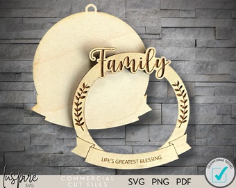 Könnte beinhalten: Ein Holz-Anhänger mit einem Kranz-Design und dem Wort "Familie" in einer dekorativen Schrift. Der Anhänger enthält auch den Text "Life's Greatest Blessing".