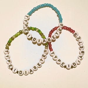 May include: Three beaded bracelets with the words "Type I Diabetes" spelled out on each. The bracelets are green, blue, and red.