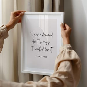 May include: A white framed print with a quote by Estée Lauder: "I never dreamed about success, I worked for it." The quote is written in black cursive script on a light grey background.