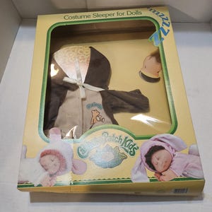 May include: A boxed doll costume sleeper set. The set includes a brown and tan hooded sleeper with a bear graphic, and a matching hat. The box features the text "Costume Sleeper for Dolls" and "Patch Kids".