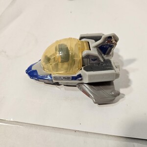 May include: A toy spaceship in shades of gray, blue, and white, with a transparent yellow cockpit. The toy has the text "XL-01" printed on the side. The spaceship is a miniature replica of a fictional vehicle.
