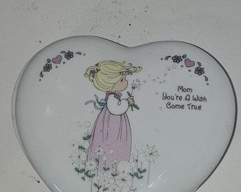 Puede incluir: Caja de baratijas en forma de corazón blanco con una ilustración de dibujos animados de una niña con un vestido rosa soplando un diente de león. El texto "Mom You're A Wish Come True" está impreso. Con flores y corazones.
