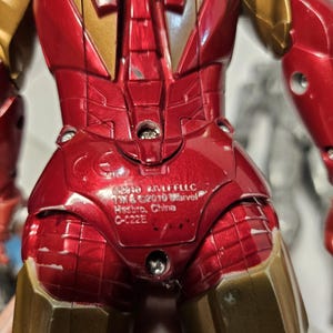May include: A red and gold Iron Man action figure. The figure has a metallic finish with visible details of the armour. The figure has the text "&copy;2010 MVLFFLLC TM & &copy;2010 Marvel Hasbro, China C-022E" printed on the back.