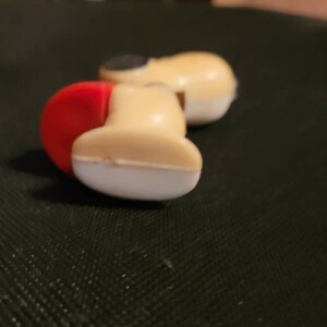 Peut inclure: Gros plan sur un jouet pistolet avec une poign&eacute;e rouge et blanche et un corps beige.