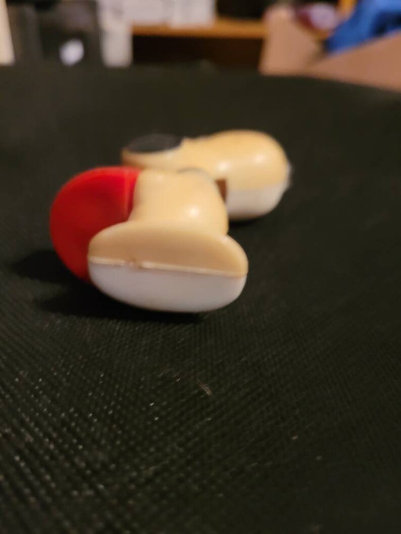 Peut inclure: Gros plan sur un jouet pistolet avec une poign&eacute;e rouge et blanche et un corps beige.